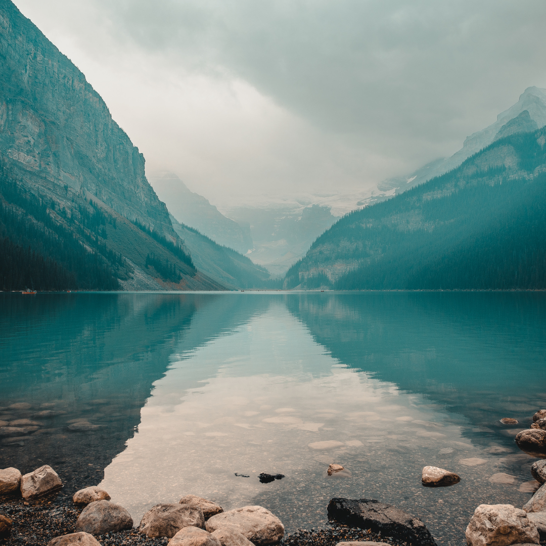 Pebbles in water surrounded by misty mountains